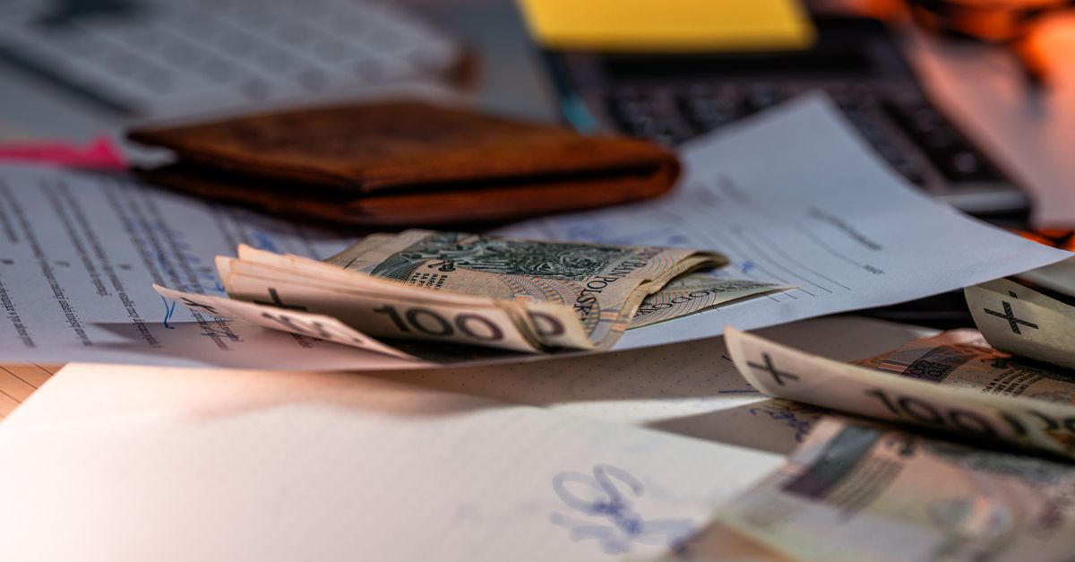 Zloty banknotes and financial paperwork scattered on a desk, representing budgeting and finance.