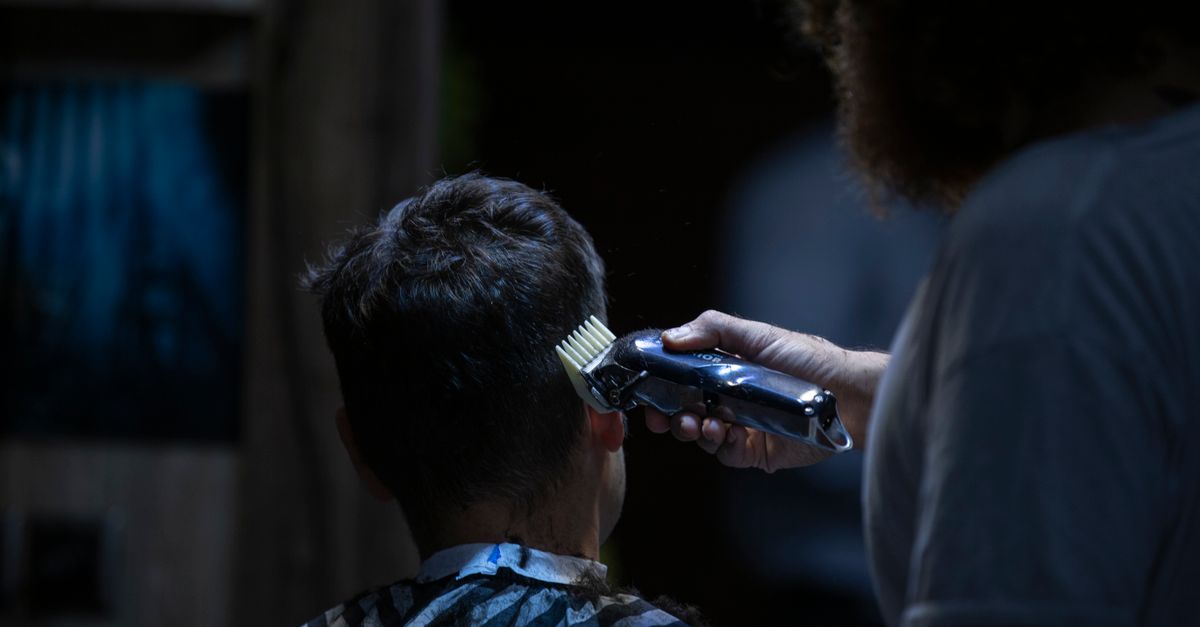 Barber using electric clipper for a precise haircut in a barber shop.