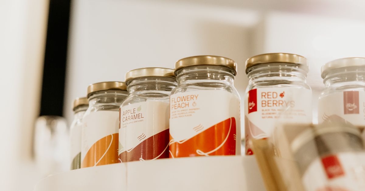Glass jars with various labels on a shelf display in a store setting.