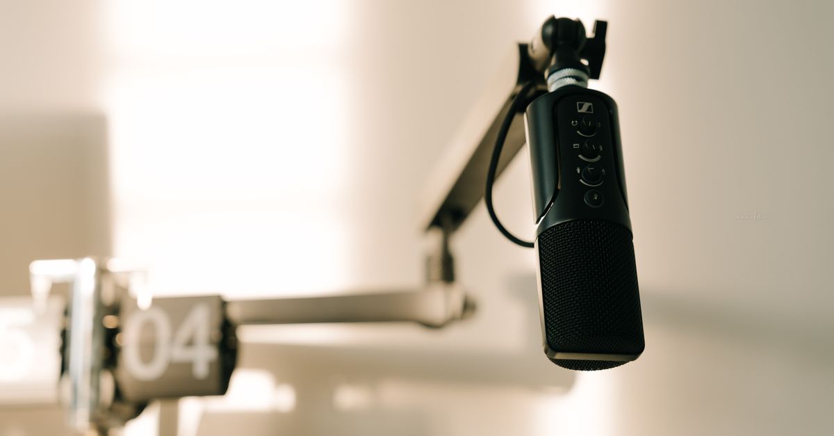 A sleek professional microphone on a boom arm in a minimalist studio.