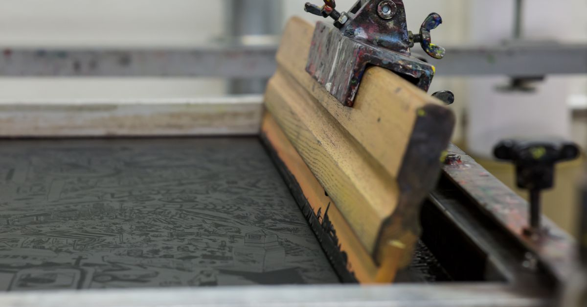 Detailed view of a screen printing setup with a wooden squeegee in Luzern, Switzerland.